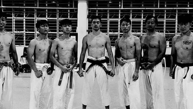Karate practitioners posing after class in gi kovan
